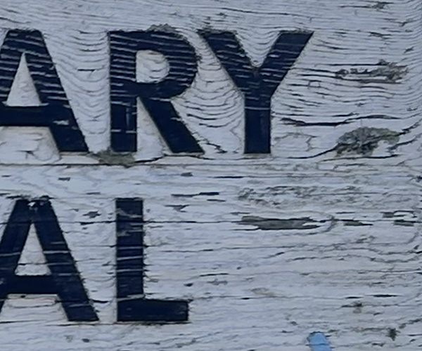 Severely weathered and split sandblasted wood lettering before restoration