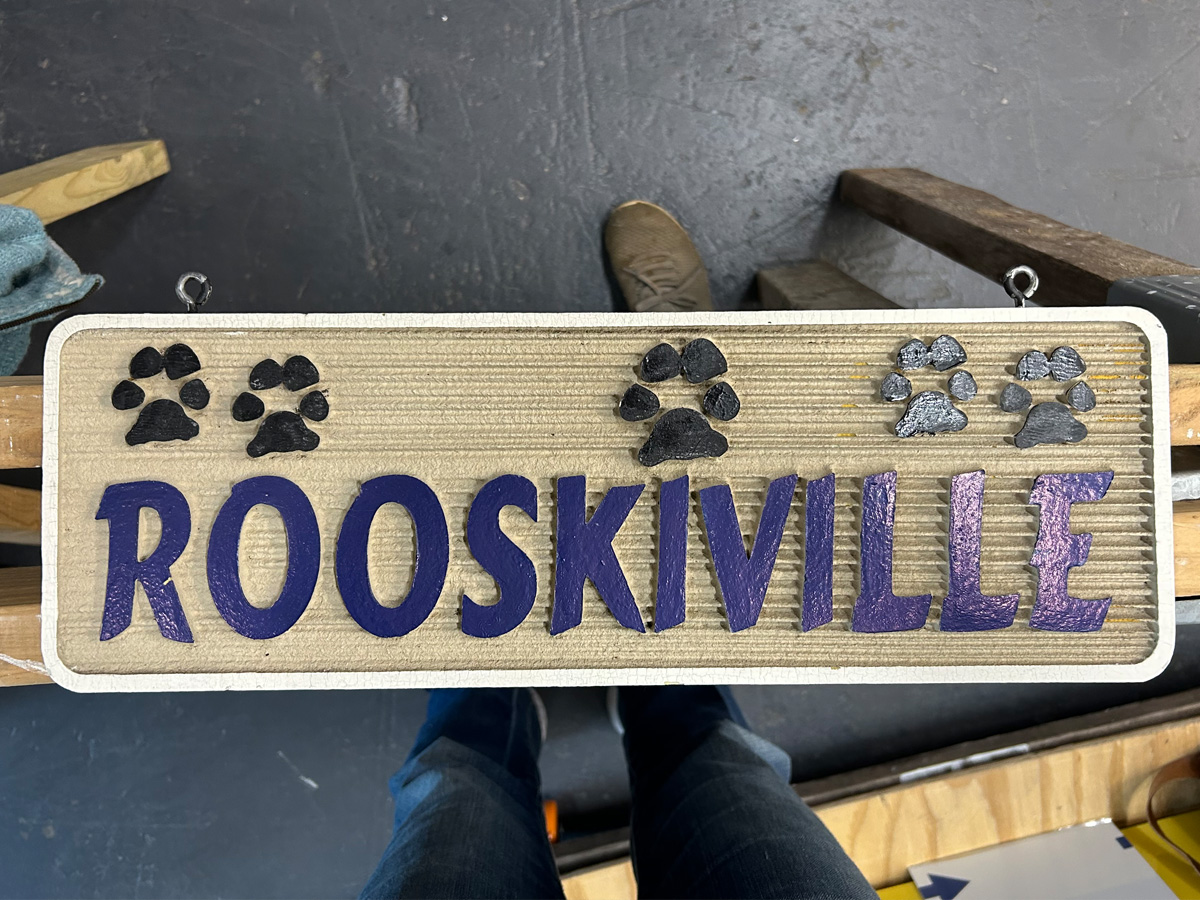 Custom carved Rooskiville wood sign with raised purple letters and paw prints in Asheville North Carolina