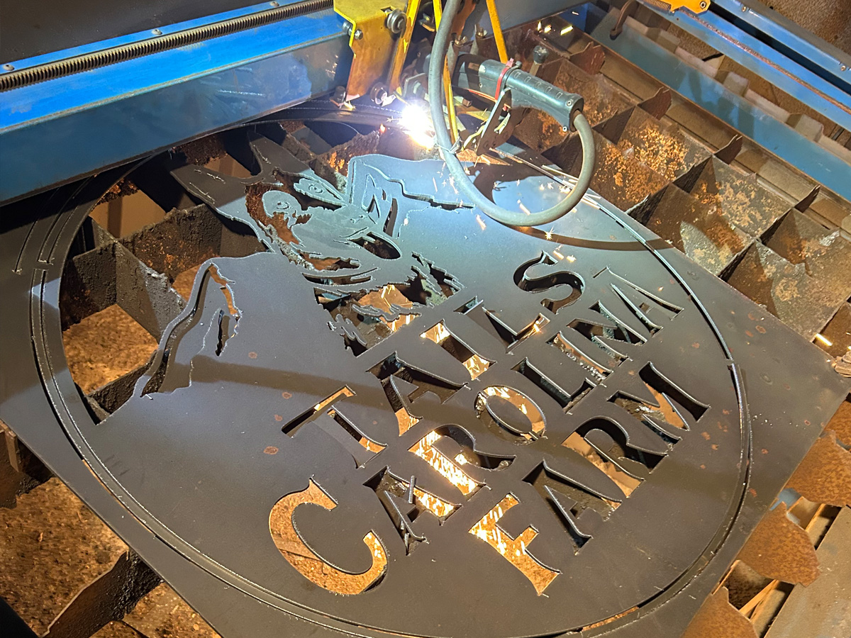 Tails Carolina Farm steel sign being cut on a CNC plasma table at Asheville Signworks