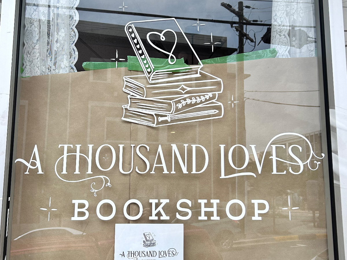 A Thousand Loves Bookshop white window graphics and decorative lettering installed on storefront glass