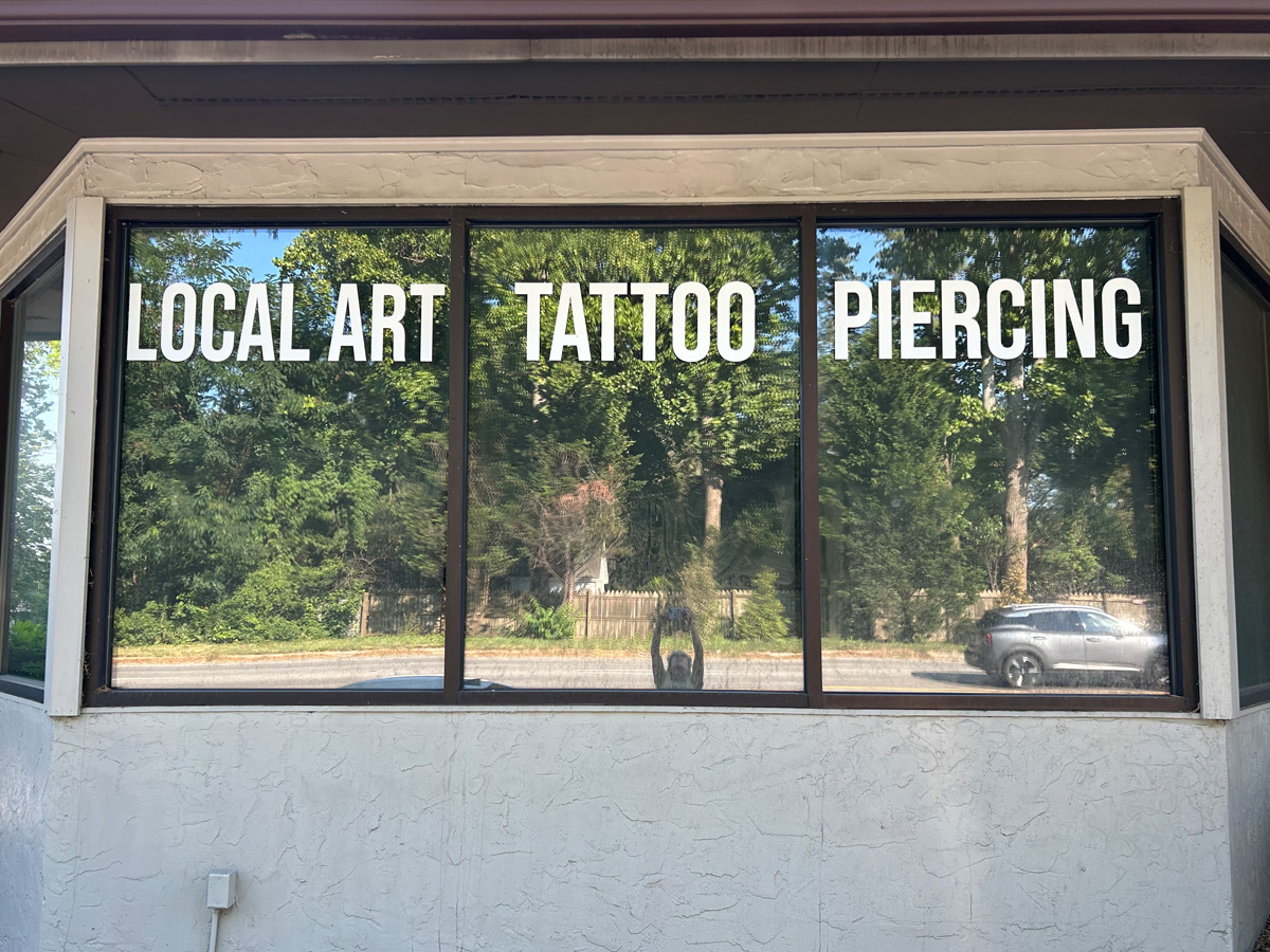 White window graphics reading Local Art Tattoo Piercing across three storefront windows